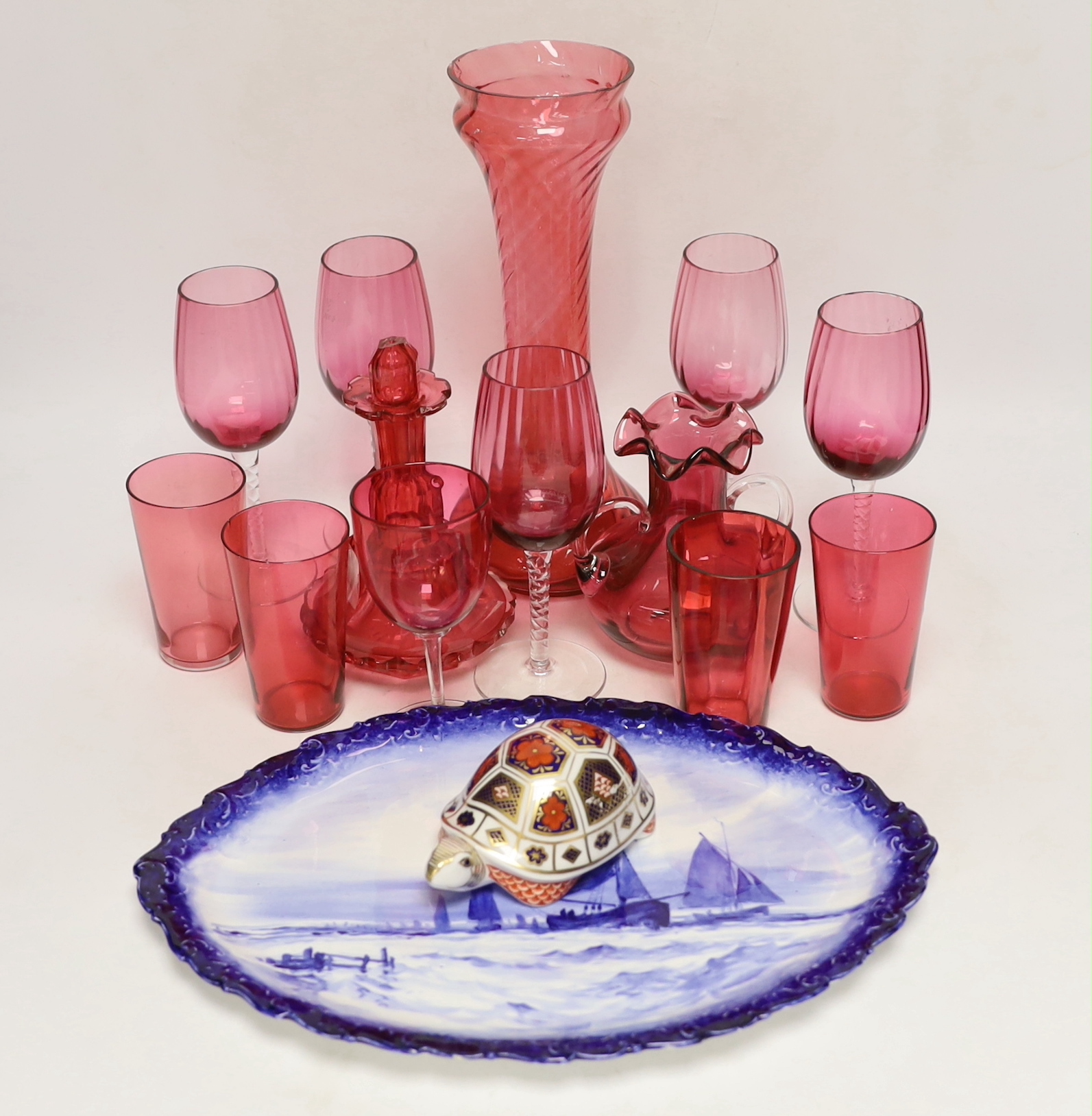 A Royal Crown Derby oval wall plate, a tortoise figure model and thirteen cranberry glass items including wine glasses, a decanter, etc. (15)